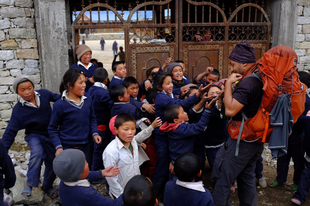 services-02 A group of schoolchildren enthusiastically gather around a trekker in rural Nepal.